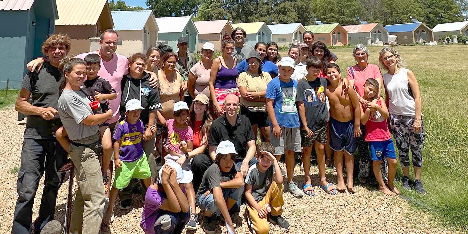 Foto grupal del equipo Tridimage y miembros de la fundación Akamasoa Argentina, reunidos frente a las viviendas coloridas del complejo.